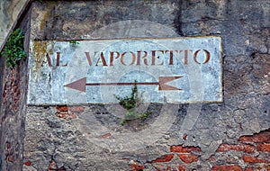 Old road sign with plants on a wall in Venice. Written in Italian Al Vaporetto