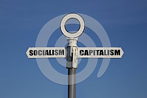 Old road sign with socialism and capitalism pointing in opposite directions