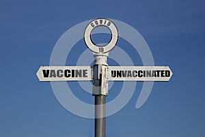 Old road sign with vaccine and unvaccinated pointing in opposite directions.  Covid 19 concept