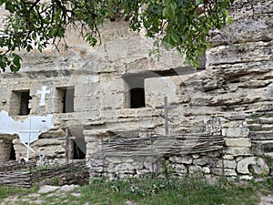 Old rock monastery. Empty window openings. Wooden cross.