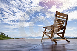 Old rocking chair by wood on wood floor. in front of the chair is Seascape