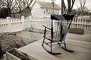 Old Rocking Chair on wooden porch with white picket fence.