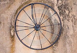 Rod iron bicycle wheel on dirty concrete wall background texture