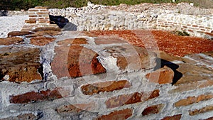 Old roman brick. The restored wall of the building of the Roman conquerors. Warm brown-red shades of uneven bricks. Archaeological