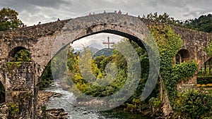 Old roman bridge in Cangas de Onis, Asturias, surrounded by a beautiful mountain landscape