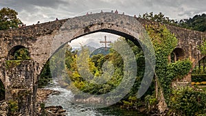 Old roman bridge in Cangas de Onis, Asturias, surrounded by a beautiful mountain landscape photo