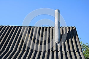 Old roof asbestos roof slates and chimney against blue sky