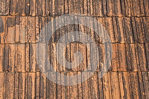 Old roof terracotta tile with black spots of mold and moss close up. rough surface texture