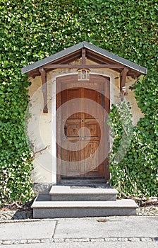 Old roofed door and overgrown house front