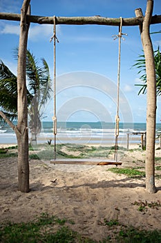 Old rope wooden swing in front of the beach