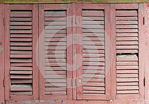 Old rose color wooden window with louver panel that peeling and damaged