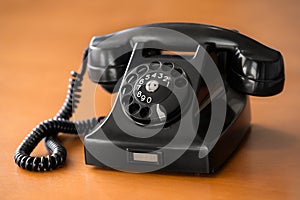 Old rotary dial phone on wooden desk