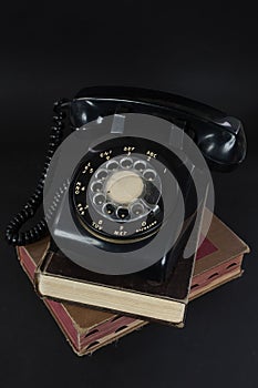 Old rotary dial telephone on books