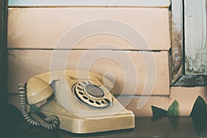 Old rotary telephone on wooden table with vintage filter background