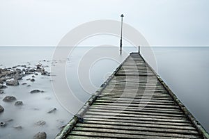 Old Rotted Jetty With Rocks And Sea Mist.
