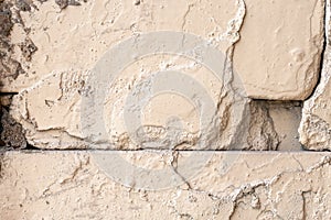 Old rough beige painted wall with cracks and holes