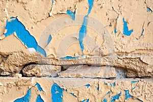 Old rough painted wall with peeling paint, cracks and holes