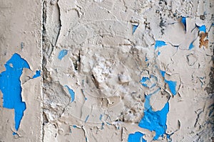 Old rough painted wall with peeling paint, cracks and holes