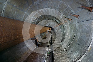 Old round dirty underground technical tunnel of heating duct with rusty pipeline
