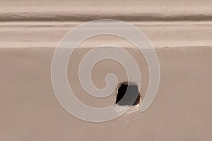 An old round hole in the wall of the facade of a city building close-up