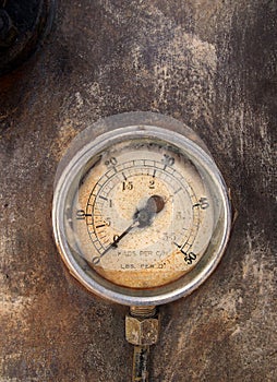 Old round pressure meter with numbers on the gauge on a rusty metal background