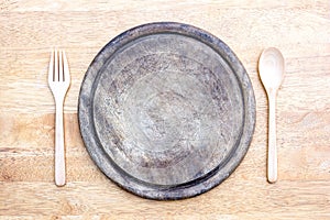 Old round wooden cutting board with spoon and fork on a table background.