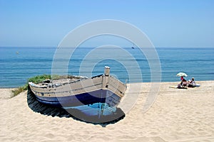 Old rowing boat on sunny white sandy beach