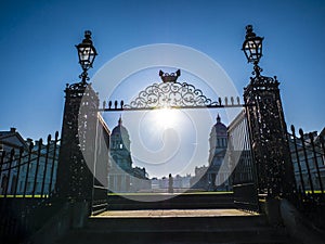 Old Royal Naval College doors entrance near Times river and the sun shining above.