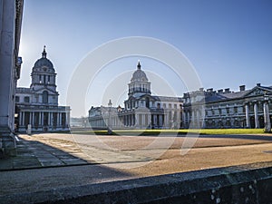 Old Royal Naval College doors entrance near Times river and the sun shining above.