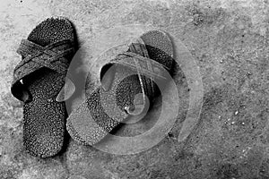 Old rubber shoes on dirty cement ground in black and white photography for background