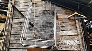 Old rubbish hangs on an old plank wall. Clothes hanger and clothes dryer. Poverty and trash.