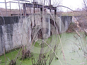 old ruined abandoned dam to discharge water into a swampy body of water a hydroengineering structure