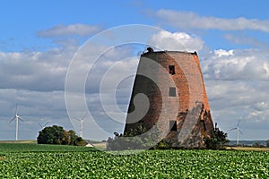 Old ruined abandoned windmill tower with electric power plant in the background