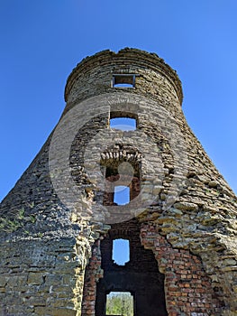 old and ruined brick windmill against blue sky on a sunny day in spring