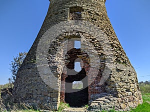 old and ruined brick windmill against blue sky on a sunny day in spring