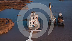 An old ruined church standing on an island under repair. A crane is working. Aerial drone shot