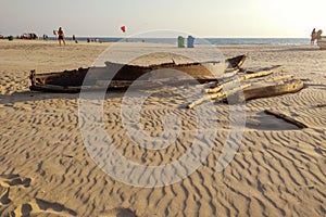 An old ruined fishing boat lies on a sandy beach.