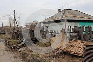 Old, ruined house in the village in a dirty fence uninhabited abandoned building