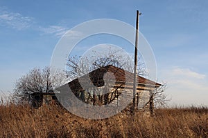 Old, ruined house in the village in a dirty fence uninhabited abandoned building