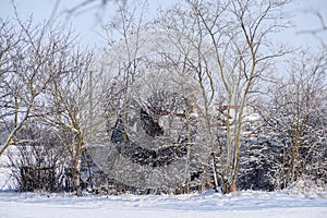 Old ruined house in the village in winter. Snow in yard.