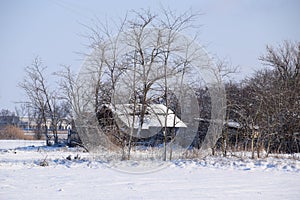 Old ruined house in the village in winter. Snow in yard.