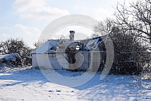 Old ruined house in the village in winter. Snow in yard.