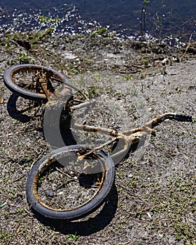 Old ruined rusted bike on a lake shore