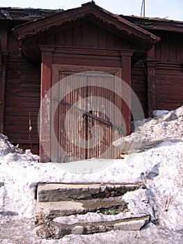 old ruined wooden house with an uninhabited unnecessary building behind a fence with closed Windows a dilapidated abandoned