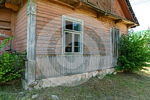 An old ruined wooden house in the village. Details of the facade of a historic wooden house with carved shutters and vintage decor