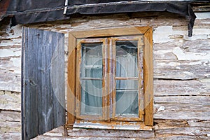 An old ruined wooden house in the village. Details of the facade of a historic wooden house with carved shutters and vintage decor