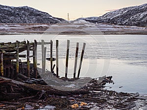 Old ruined wooden pier in the bay of the Barents Sea. Teriberka. Pollution of the coastline