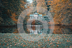 an old, run down house is reflected in the water on a fall day