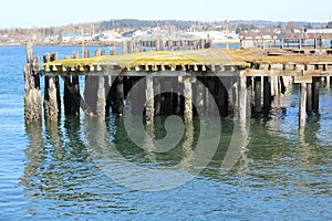 An old run down pier in a bay and a view of an old town