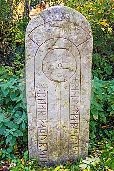 Old Runestone with runes and a cross in nature